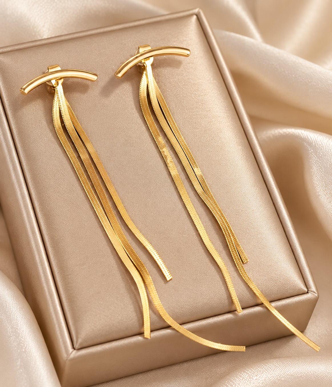 Aretes ráfaga dorada largos y minimalistas de Nia-Vanity, con diseño elegante y acabado brillante sobre fondo neutro.