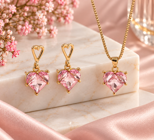 Set de collar y aretes con corazones rosa y cristales en marco dorado, de Nia-Vanity, visible con detalles elegantes y brillantes.