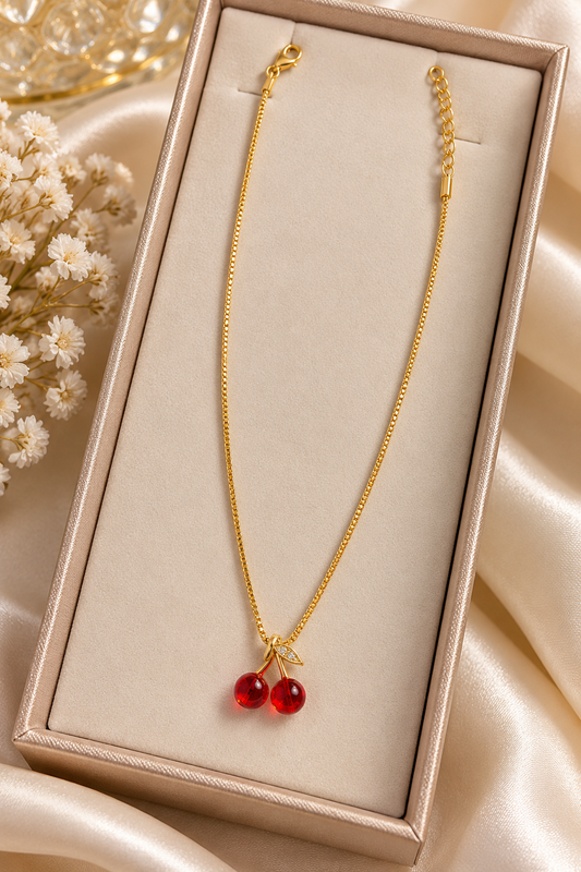 Collar de cereza de la marca Nia-Vanity con diseño delicado y detalles en forma de cereza, en tonos rojos y plateados.